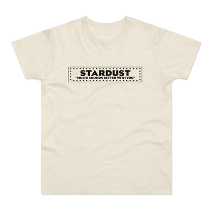 A cream-colored short-sleeved t-shirt features a black rectangular graphic on the chest with the text STARDUST and MUSIC SOUNDS BETTER WITH YOU surrounded by a border of stars.