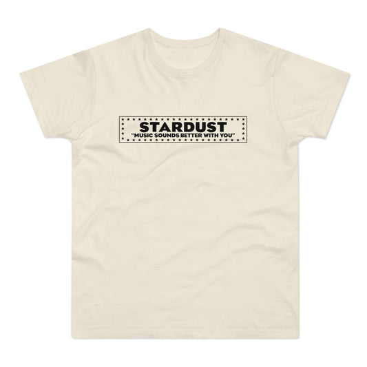 A cream-colored short-sleeved t-shirt features a black rectangular graphic on the chest with the text STARDUST and MUSIC SOUNDS BETTER WITH YOU surrounded by a border of stars.
